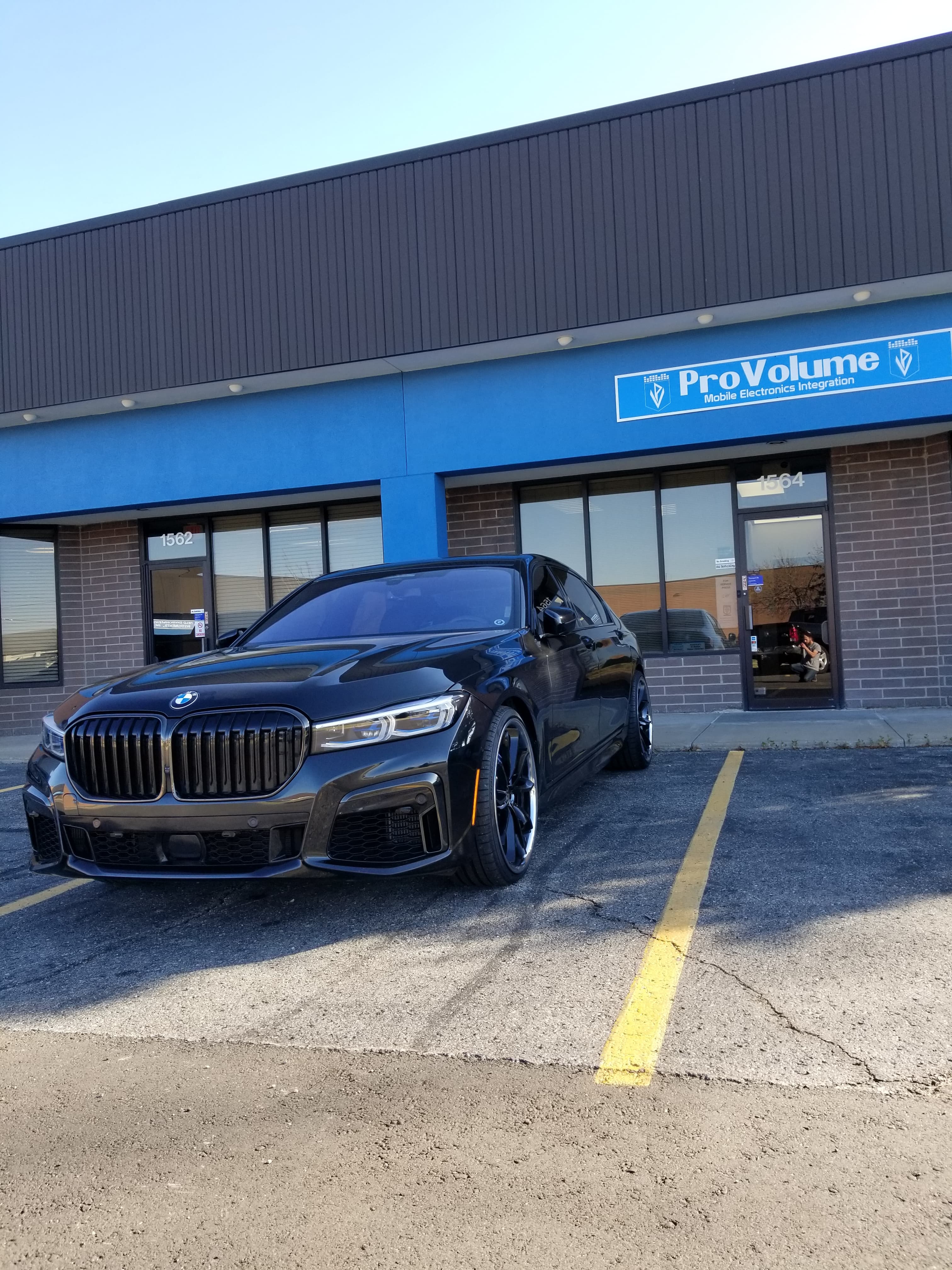 Sleek black BMW sedan parked in front of a ProVolume mobile electronics store.